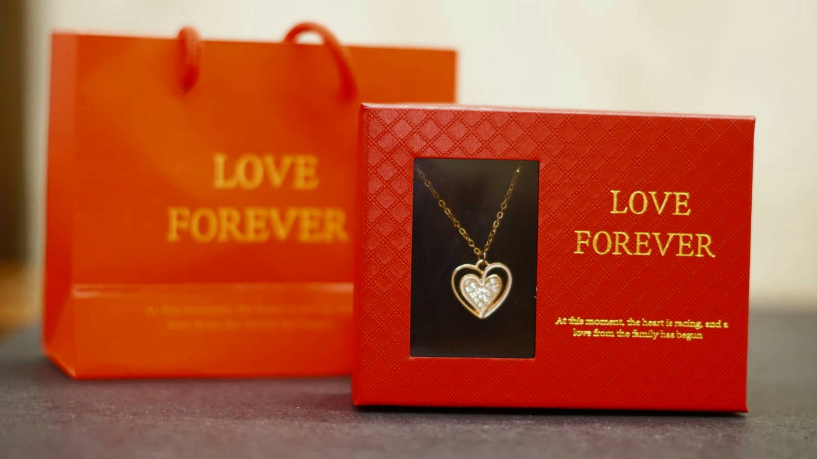 Love Forever heart pendant necklace set in a red gift box with decorative artificial flowers.
